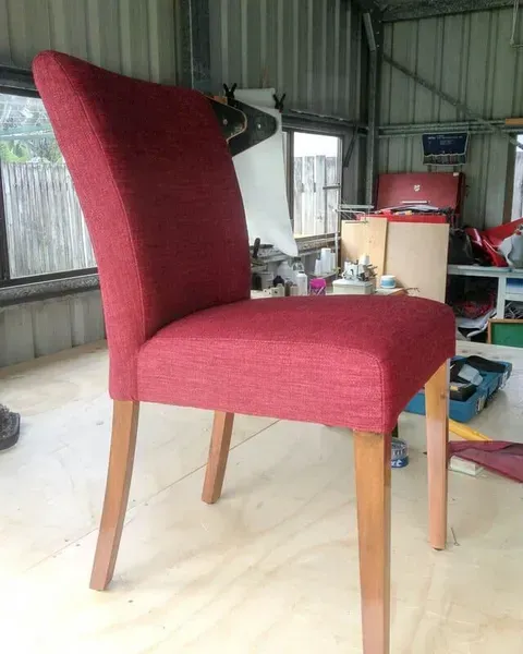 A Red Chair is on a Wooden Floor in a Room — Paulie's Upholstery in Edmonton, QLD