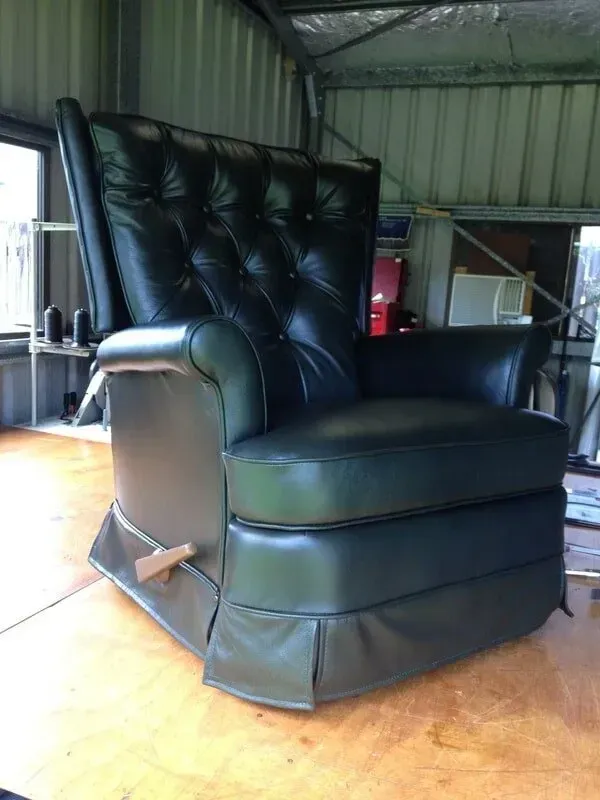 A Black Leather Recliner is on a Wooden Floor in a Room — Paulie's Upholstery in Edmonton, QLD