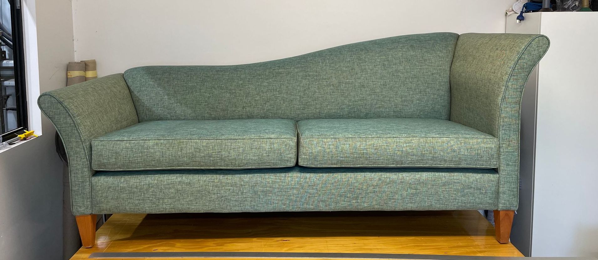 A Green Couch is on a Wooden Table in a Room — Paulie's Upholstery in Edmonton, QLD