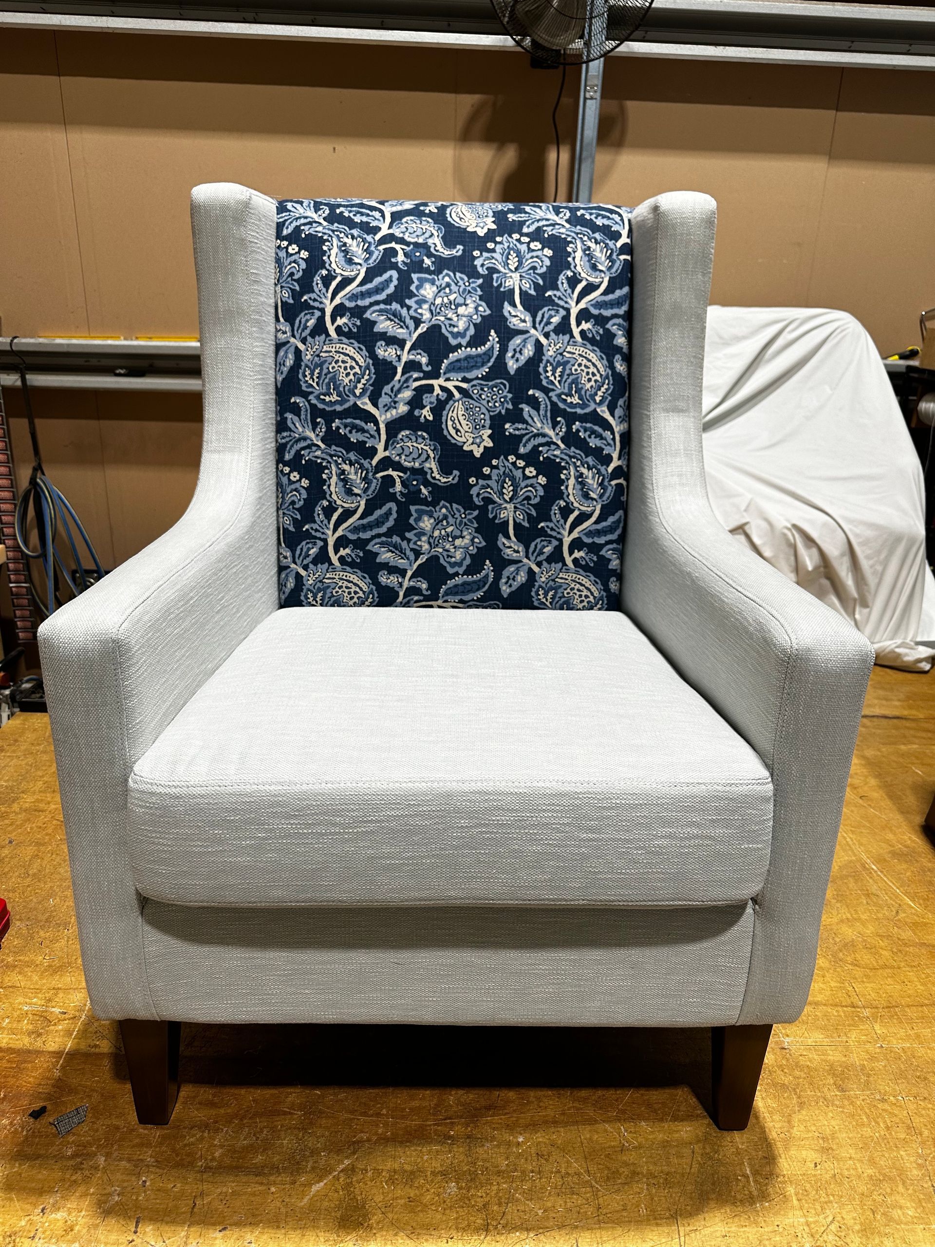 A Grey Chair With A Blue Patterned Cushion On A Wooden Floor— Paulie's Upholstery in Edmonton, QLD