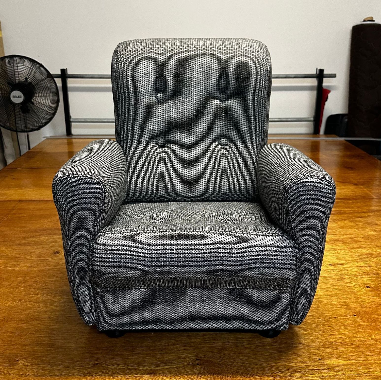 A Grey Couch On A Wooden Floor— Paulie's Upholstery in Edmonton, QLD