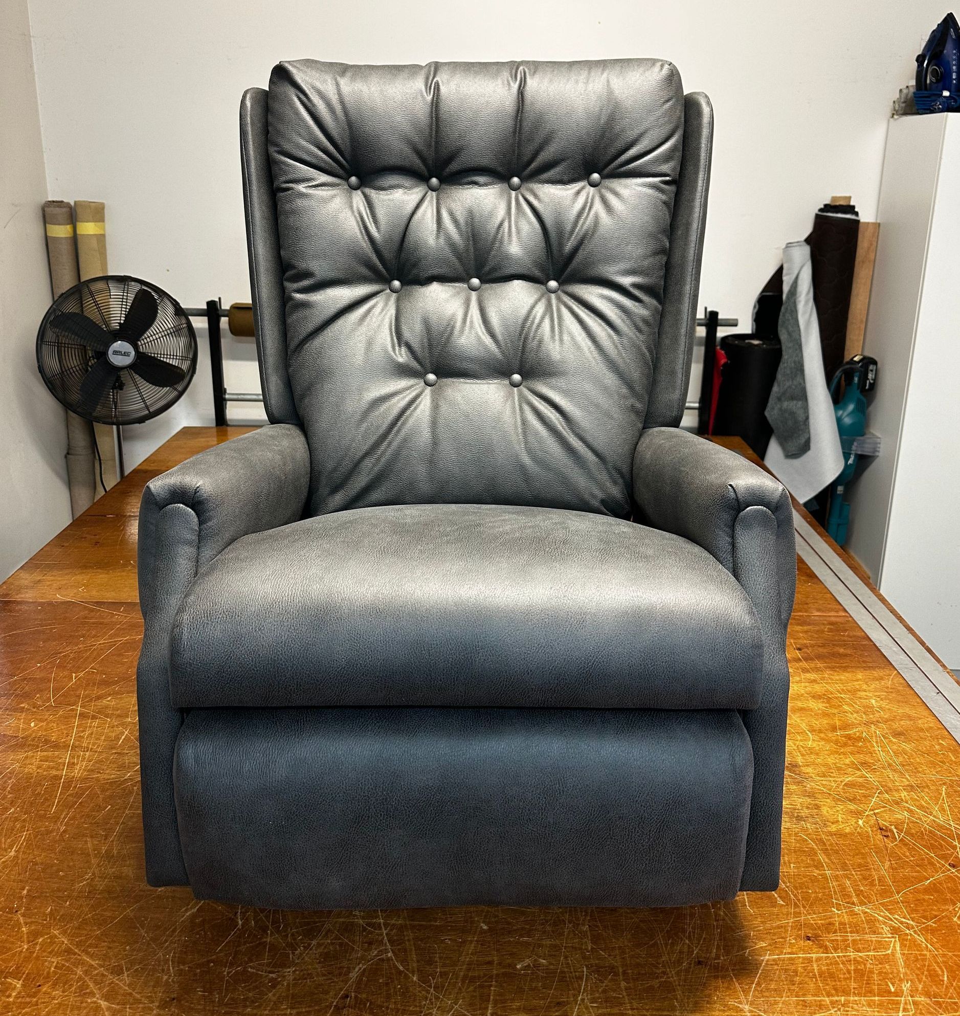 A Black Leather Couch Recliner Chair On A Wooden Floor — Paulie's Upholstery in Edmonton, QLD