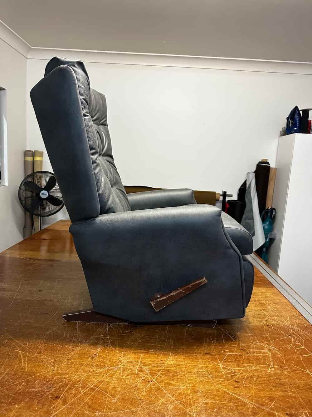 A Black Leather Recliner Is Sitting On A Wooden Floor In A Living Room — Paulie's Upholstery in Edmonton, QLD