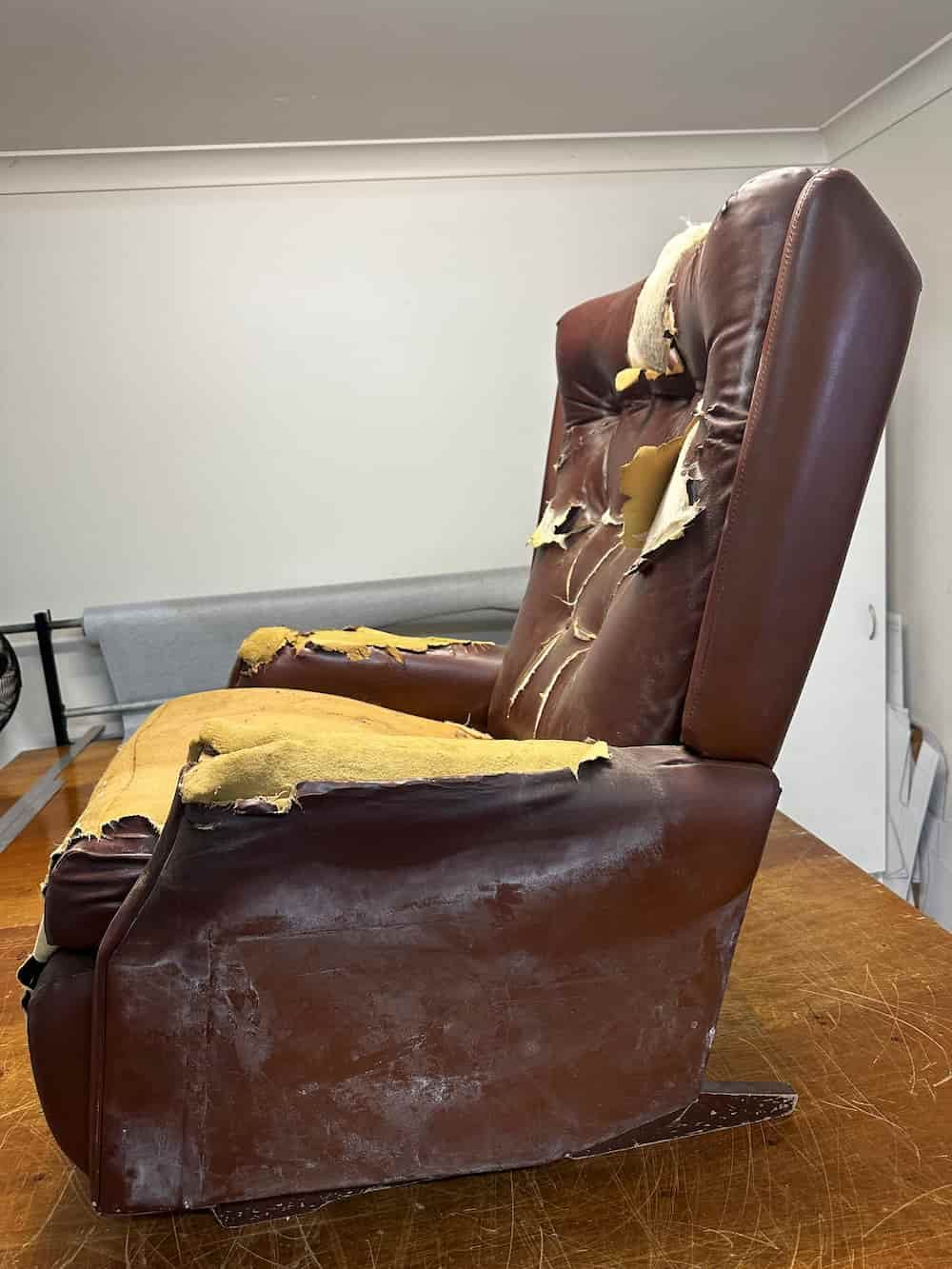 A Brown Leather Recliner Is Sitting On Top Of A Wooden Table — Paulie's Upholstery in Edmonton, QLD