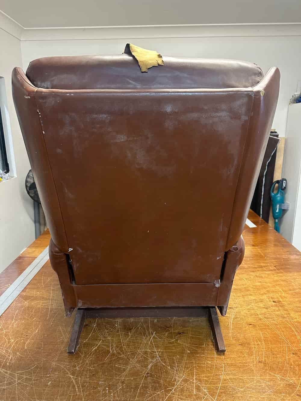 A Brown Leather Chair Is Sitting On Top Of A Wooden Table — Paulie's Upholstery in Edmonton, QLD
