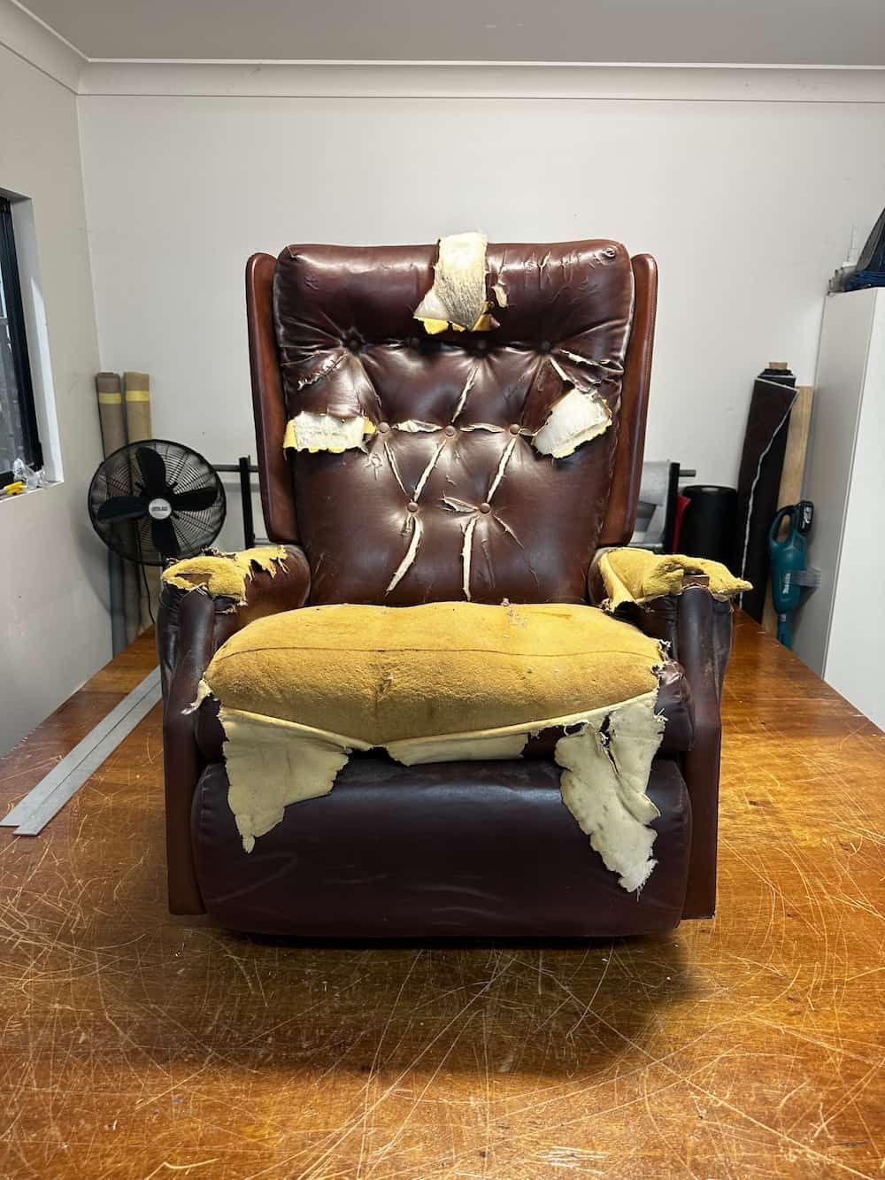 A Brown Leather Recliner Is Sitting On A Wooden Floor In A Room — Paulie's Upholstery in Edmonton, QLD