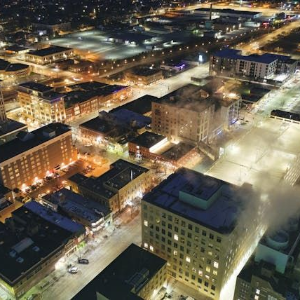 Aerial night view of a city downtown with illuminated streets and buildings.
