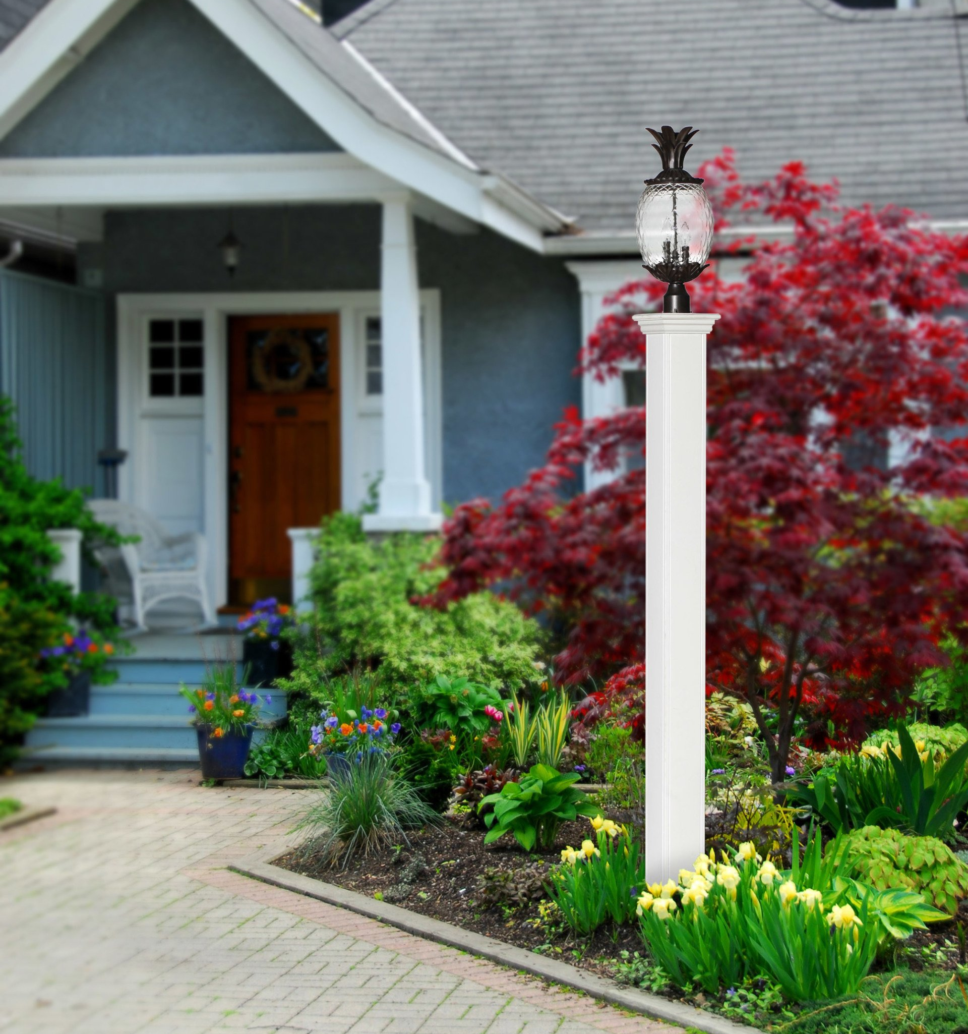 Front walkway to a house with colorful landscaping and a white lamp post near the entrance