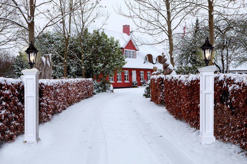 A snowy driveway leading to a red house