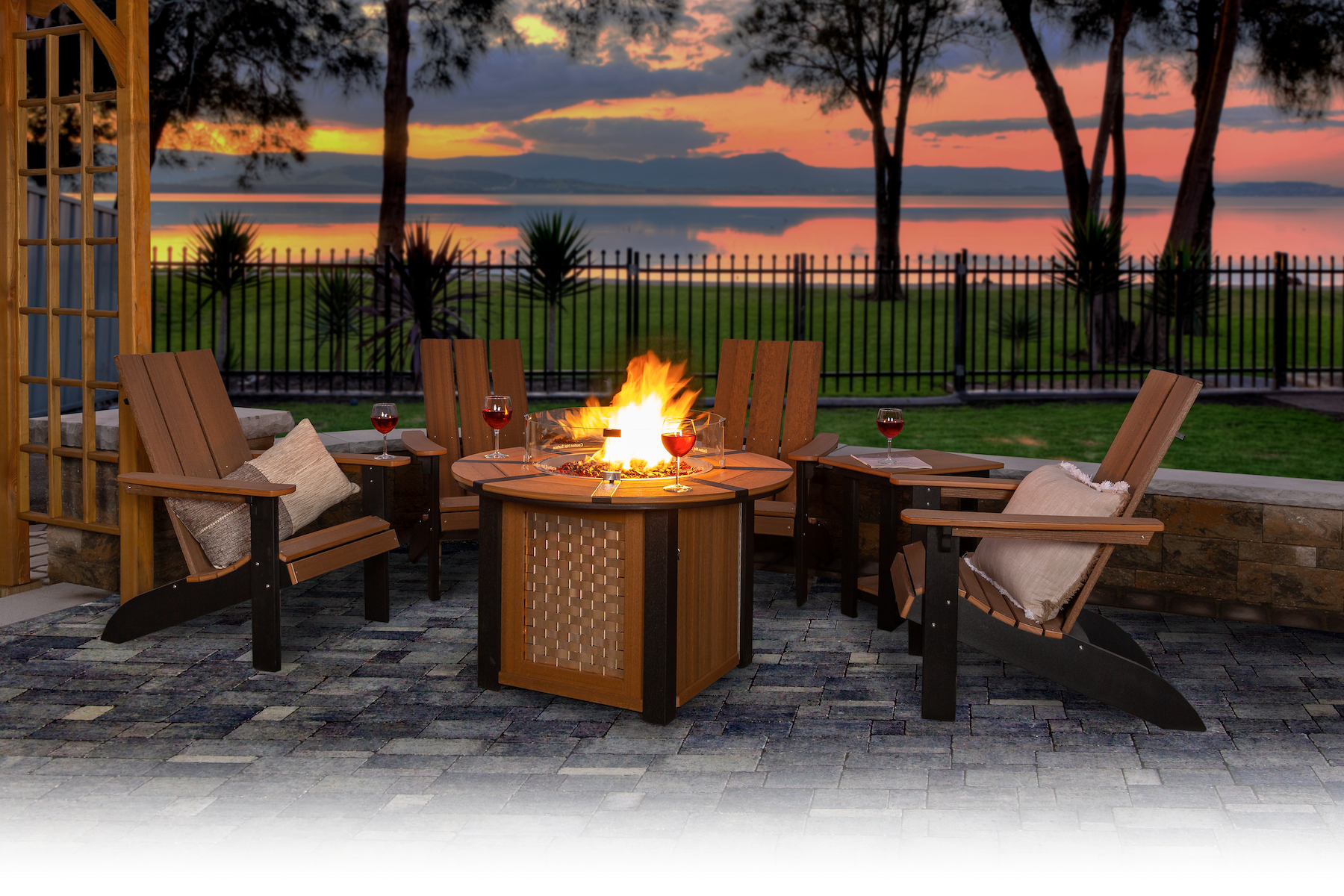 A fire pit is surrounded by chairs on a patio at sunset.