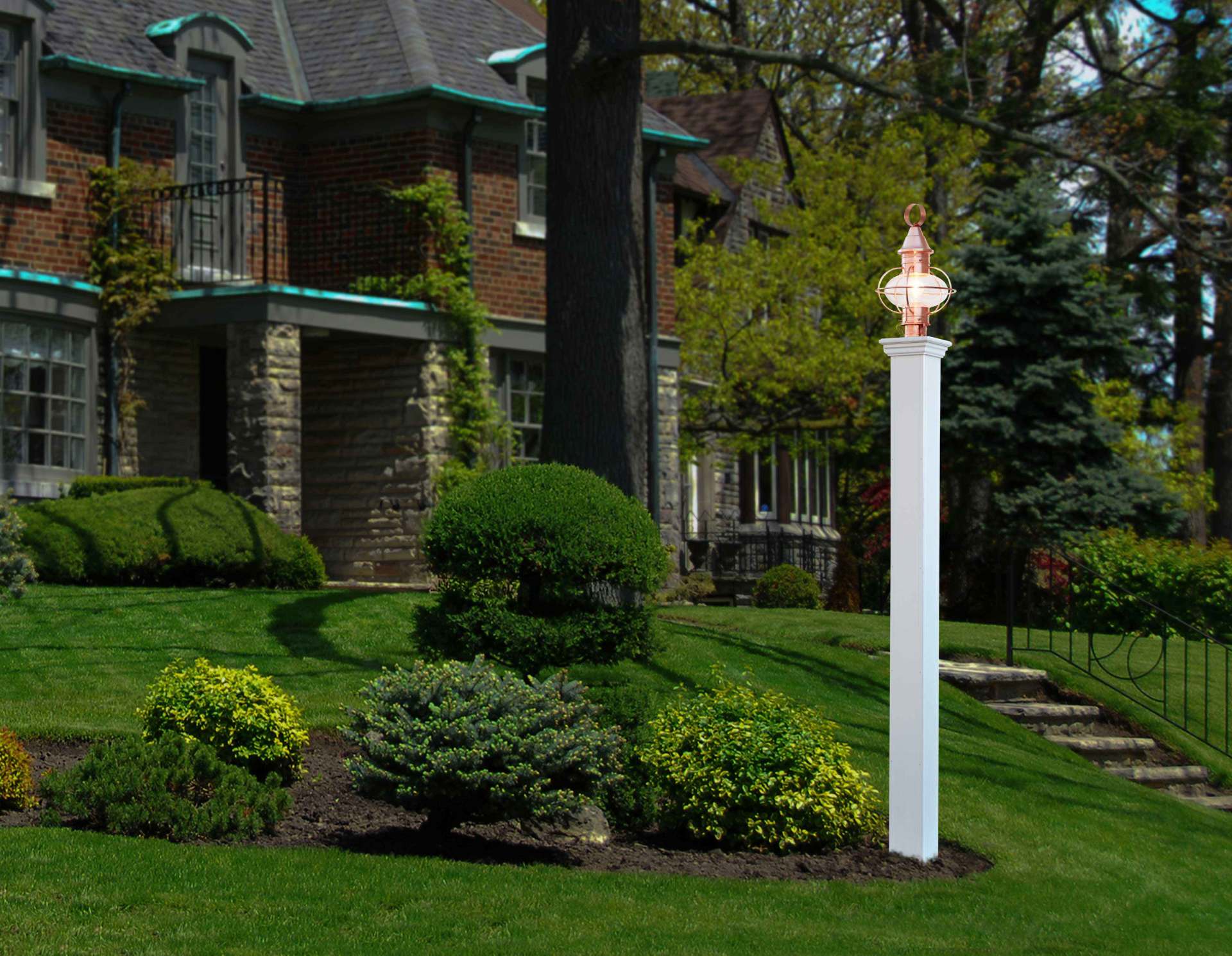 White mailbox on a suburban sidewalk beside a row of houses and flower beds