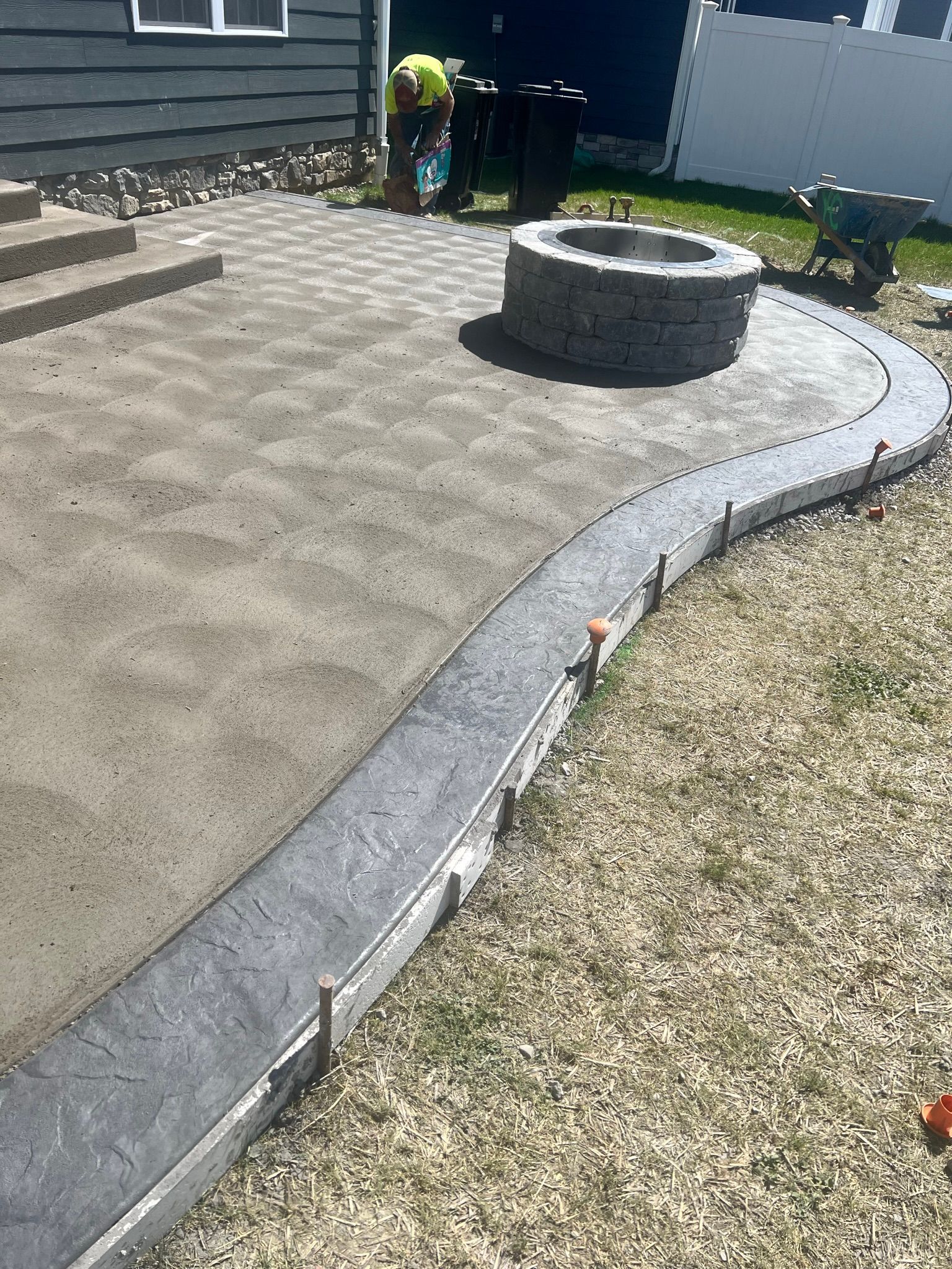 A concrete patio with a fire pit in the middle of it.
