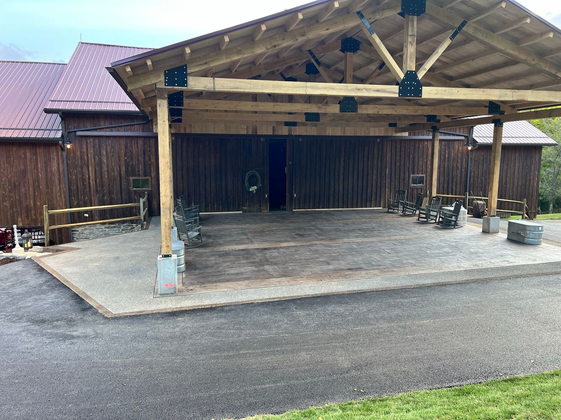 A large wooden barn with a covered area in front of it.