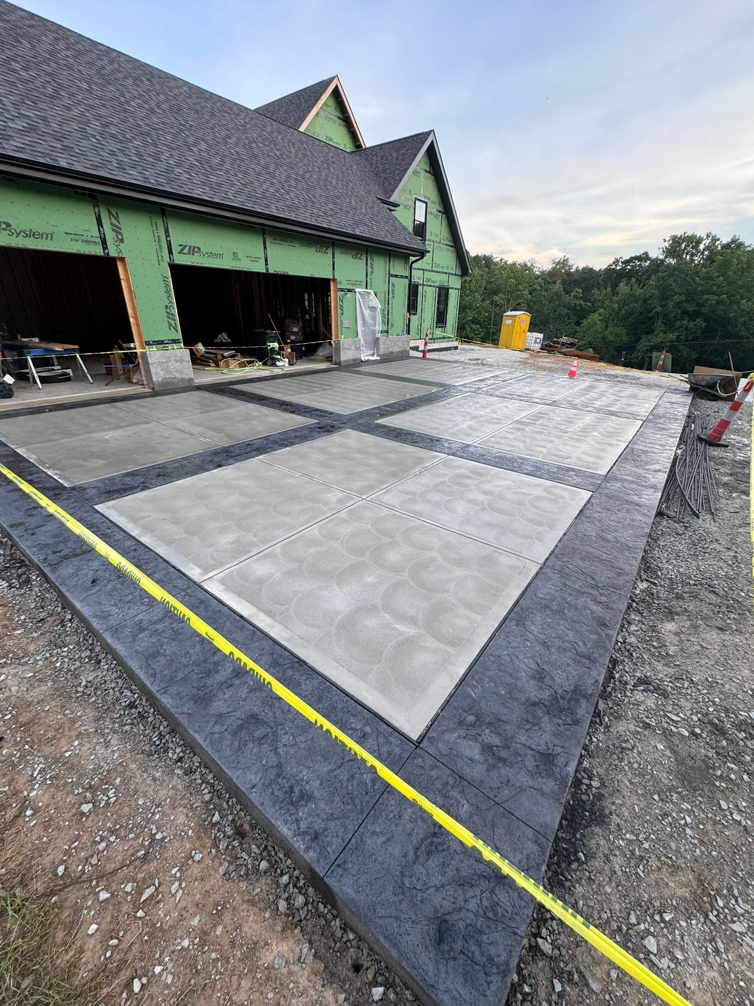 A large concrete driveway is being built in front of a house under construction.