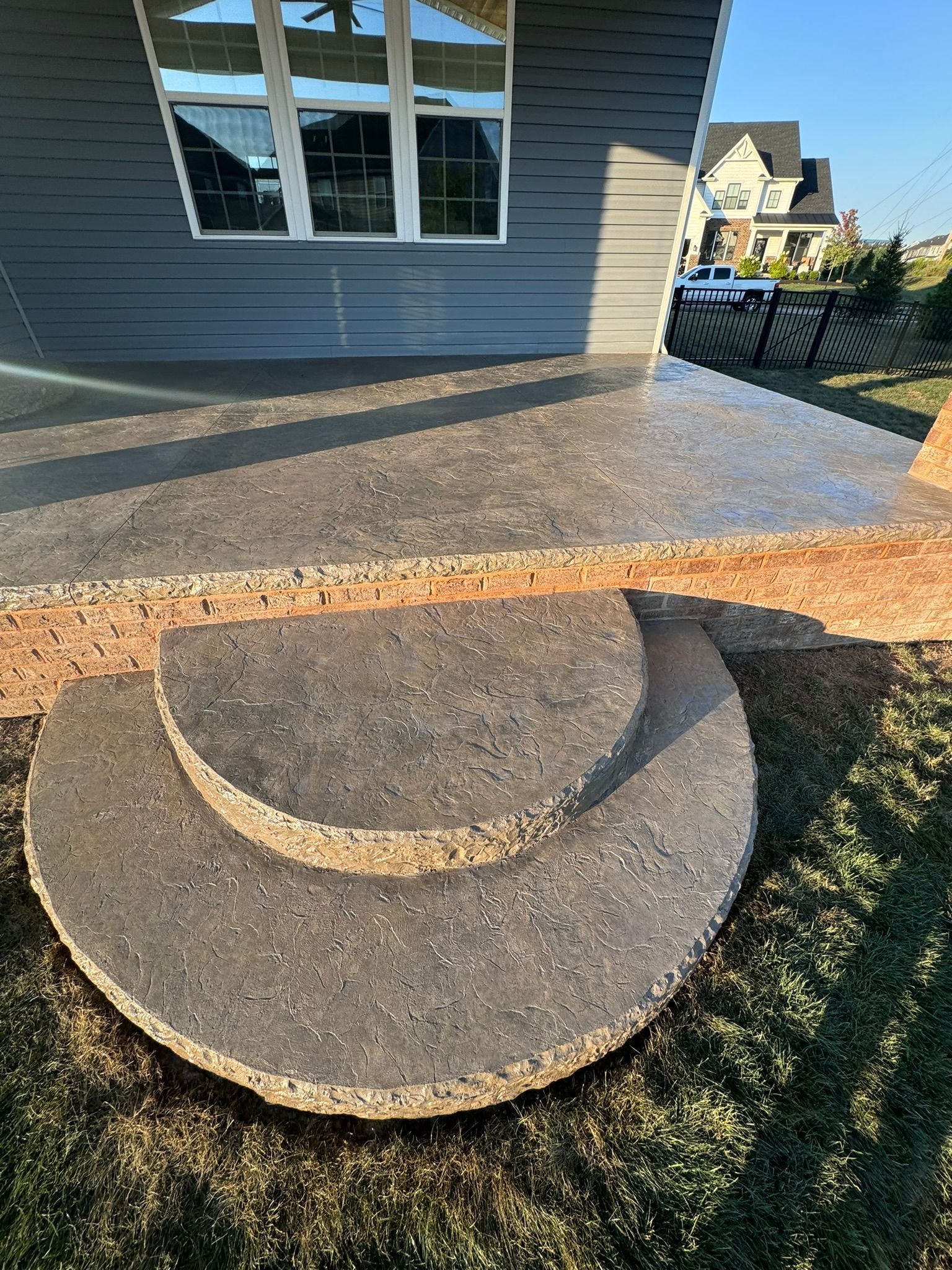 A concrete table is sitting in the grass in front of a house.