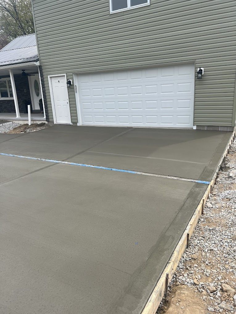 A concrete driveway is being built in front of a house with a garage door.