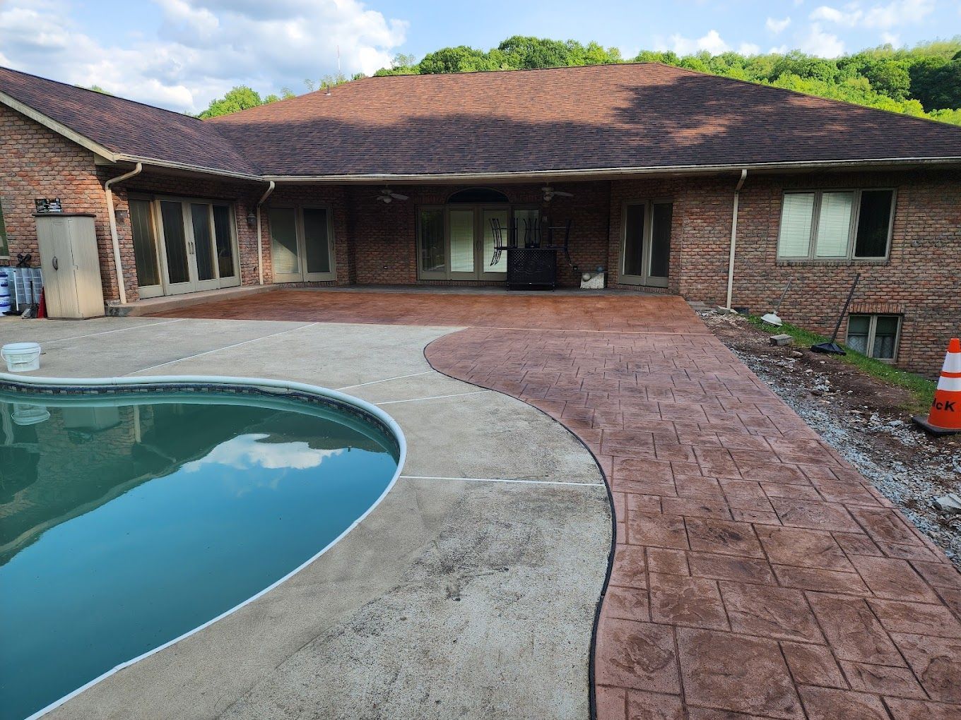 A brick house with a swimming pool in front of it.