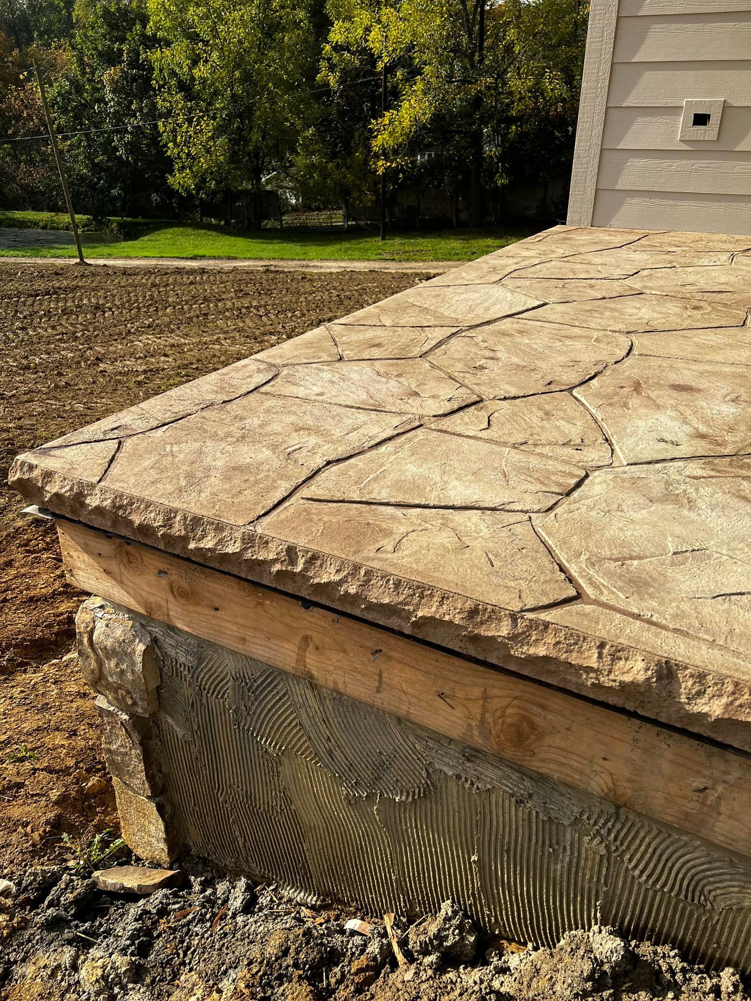 A stone walkway is being built in front of a house.
