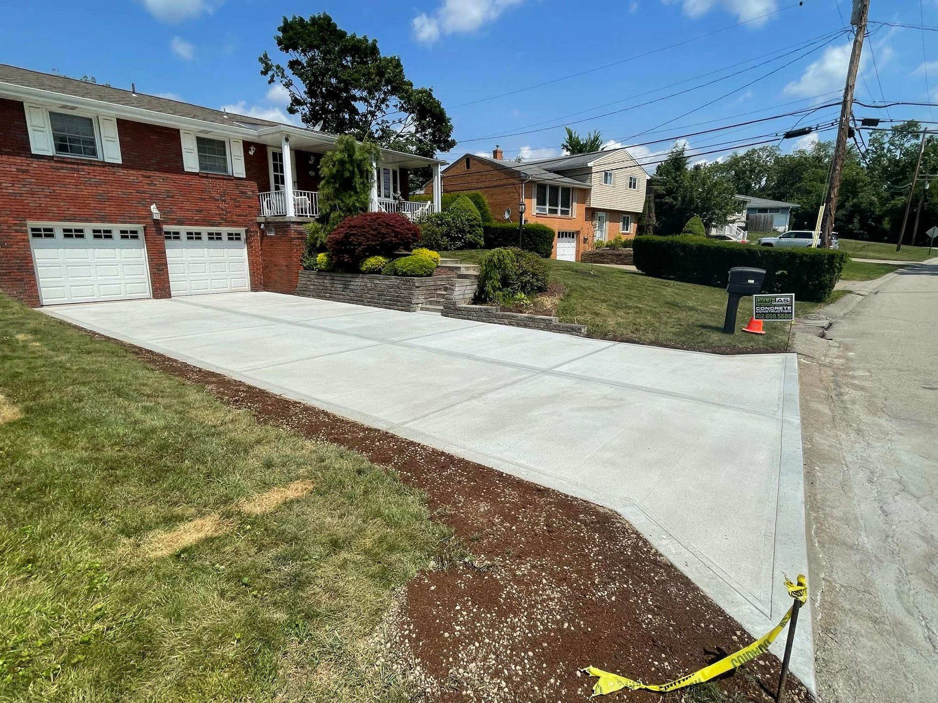 A concrete driveway is being built in front of a brick house.