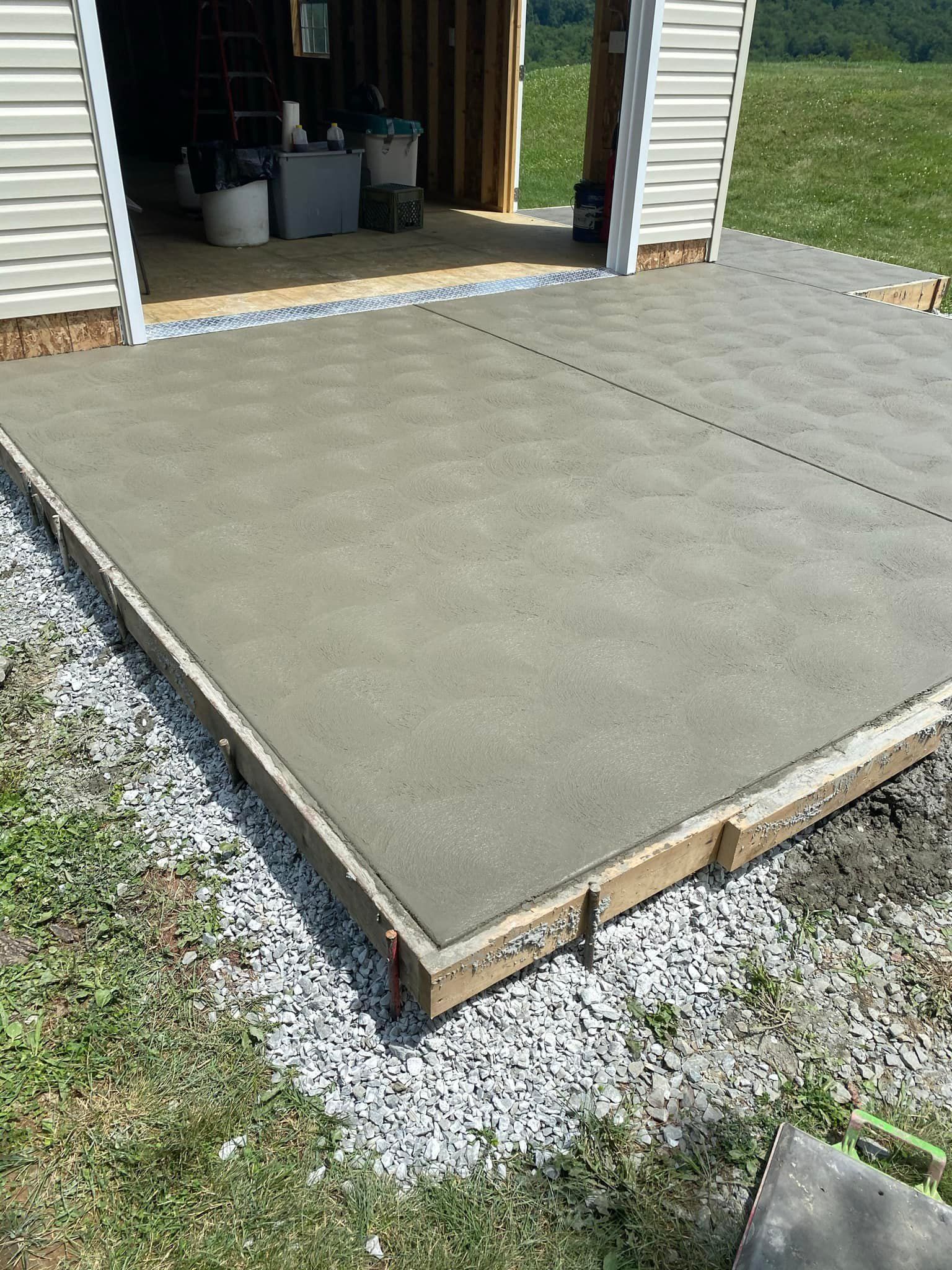A concrete patio is being built in front of a garage.