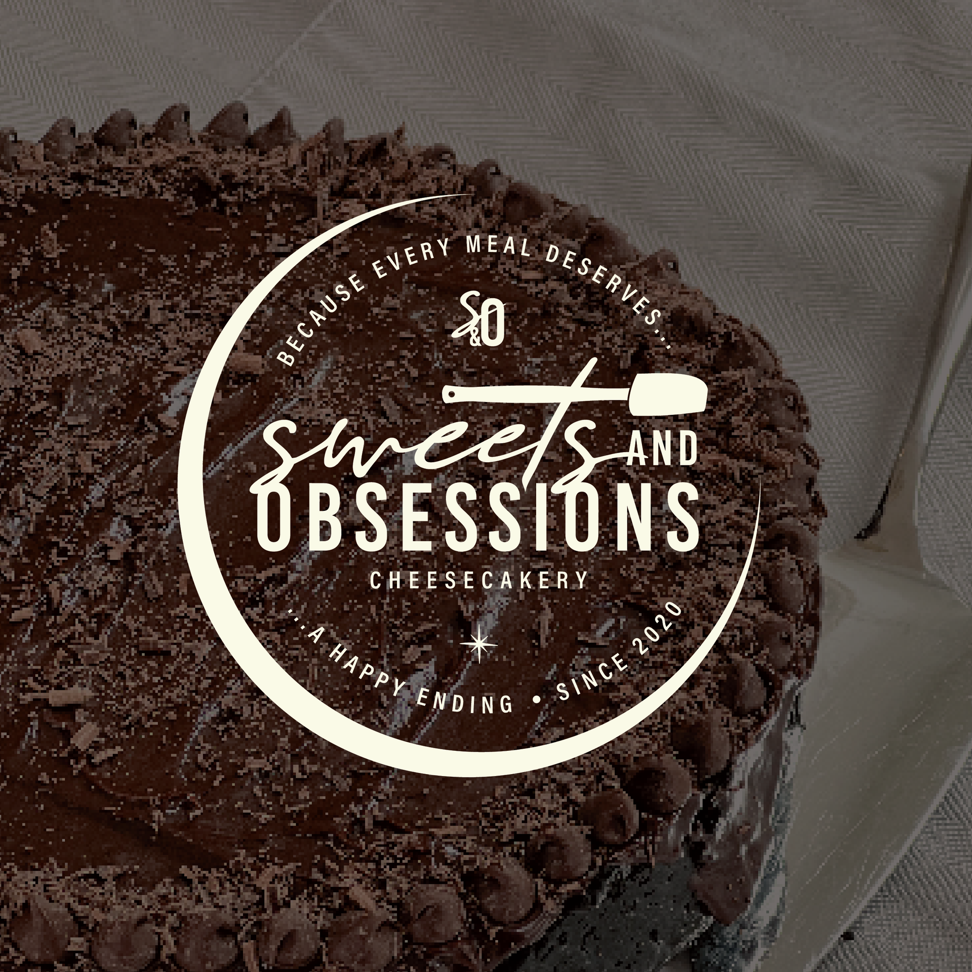 Chocolate cake with white “Sweets and Obsessions” bakery logo on top
