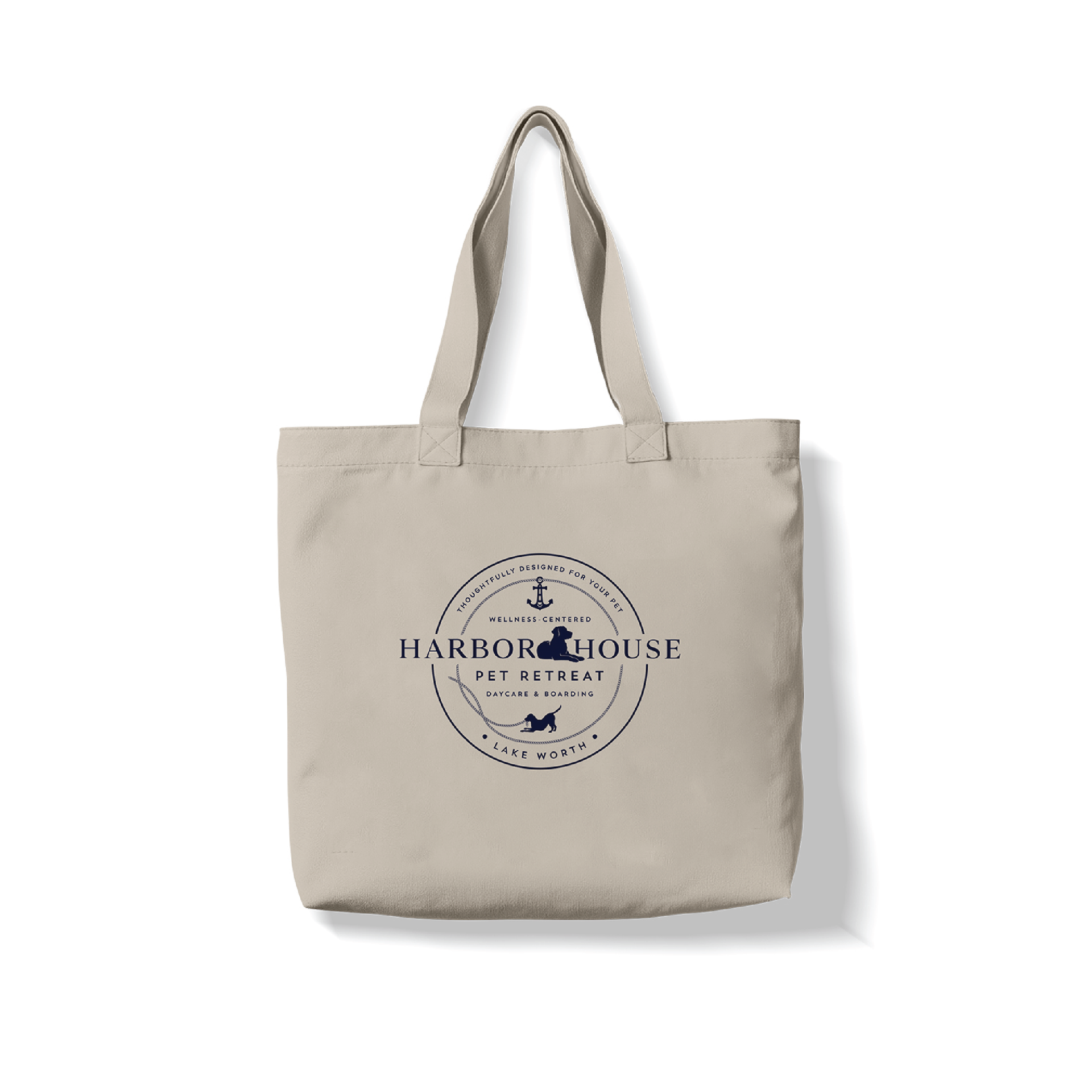 Beige tote bag with handles and a navy Harbor House logo on the front