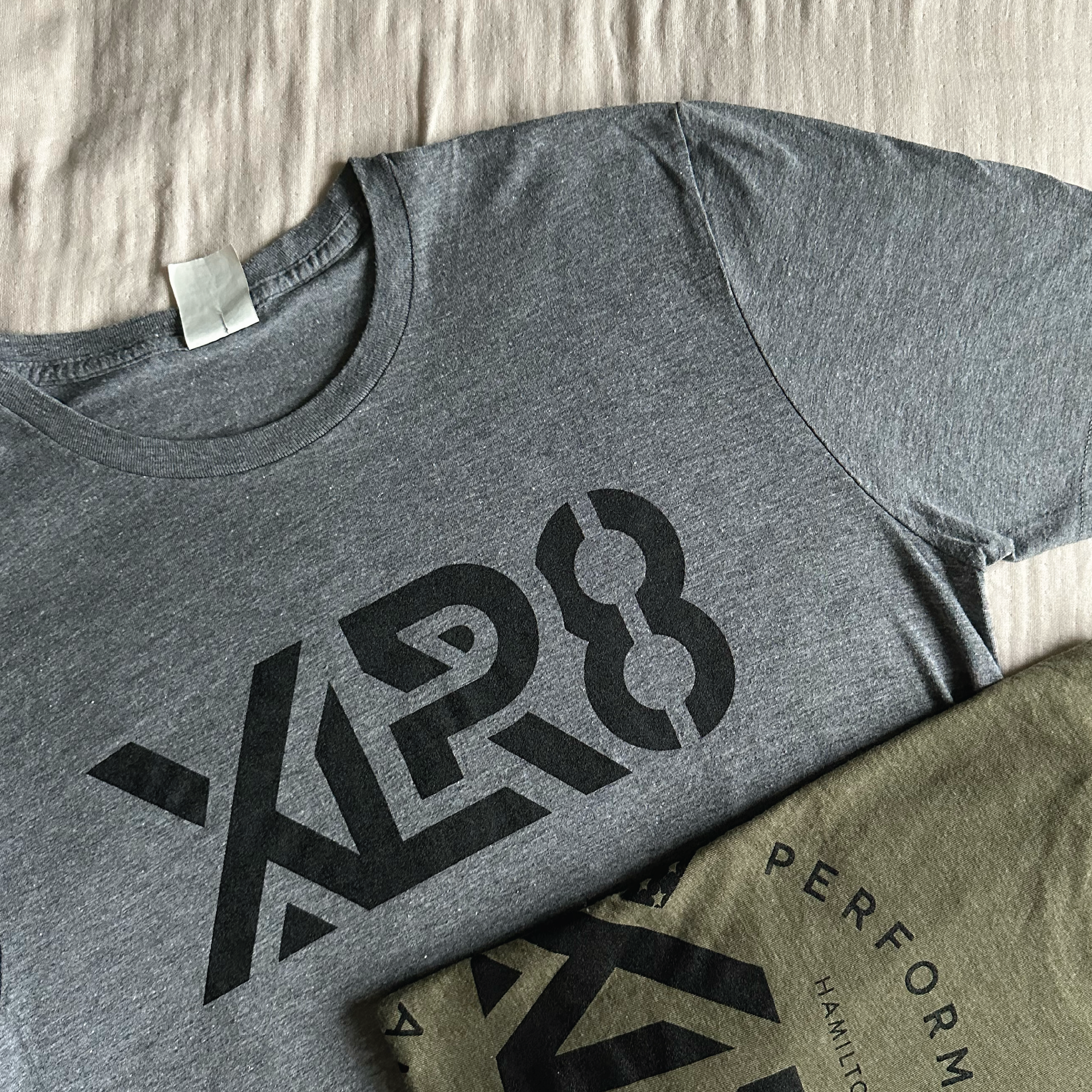 Gray T-shirt with bold black “XPRO” graphic laid on a white textured surface