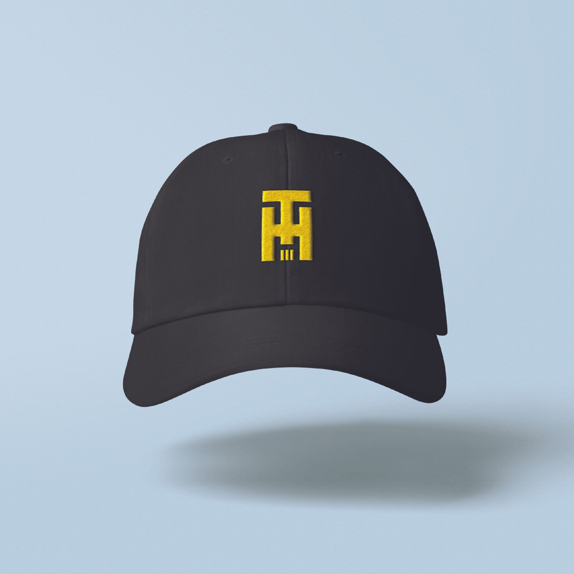 Black baseball cap with a yellow TH logo on a light blue background