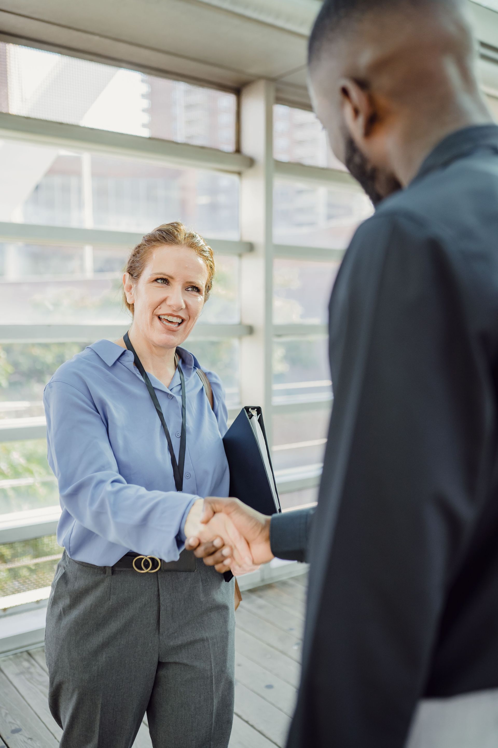 Two professionals shaking hands in a bright office corridor