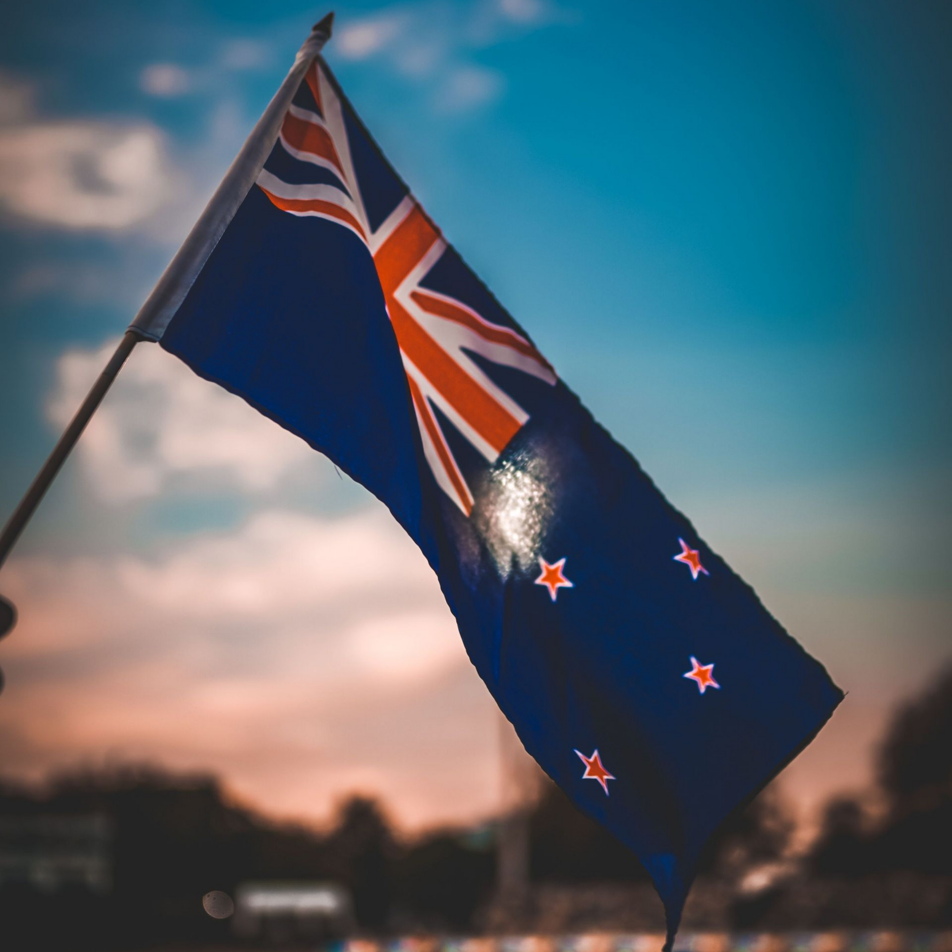 New Zealand flag waving against a sunset sky