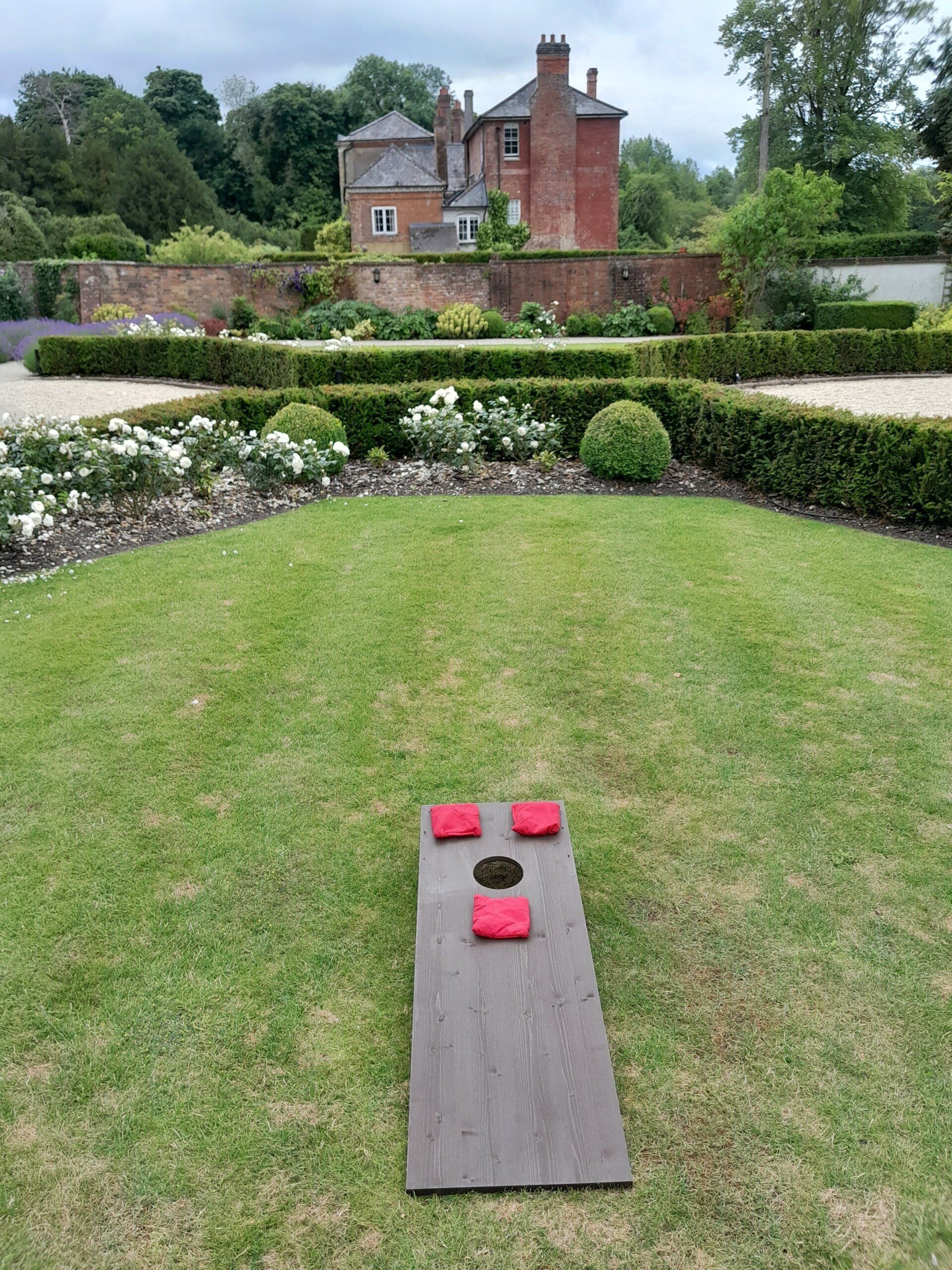 Wooden Cornhole lawn game on grass at a hotel for a wedding.