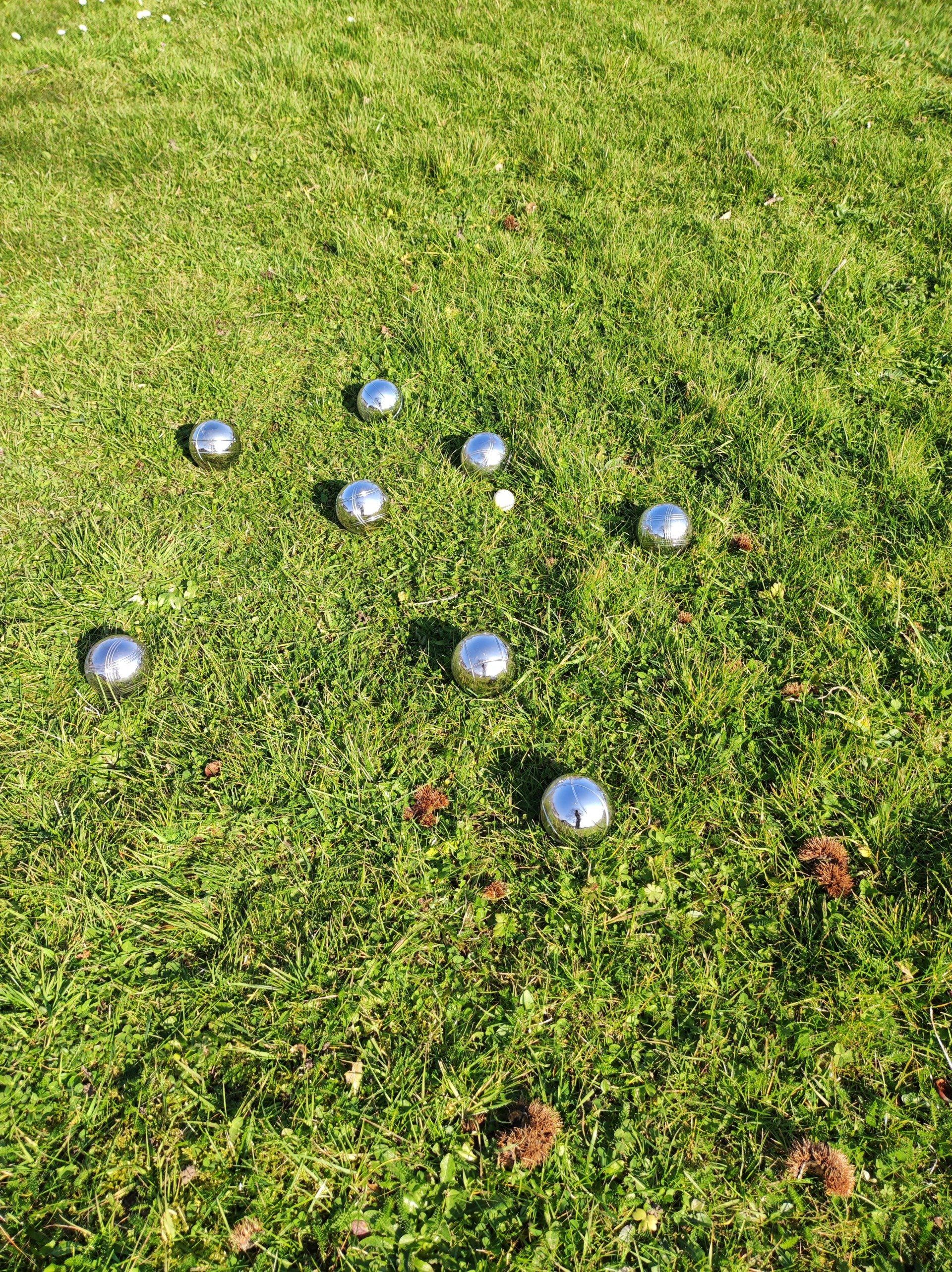 8 French Boules balls on grass after they have been thrown