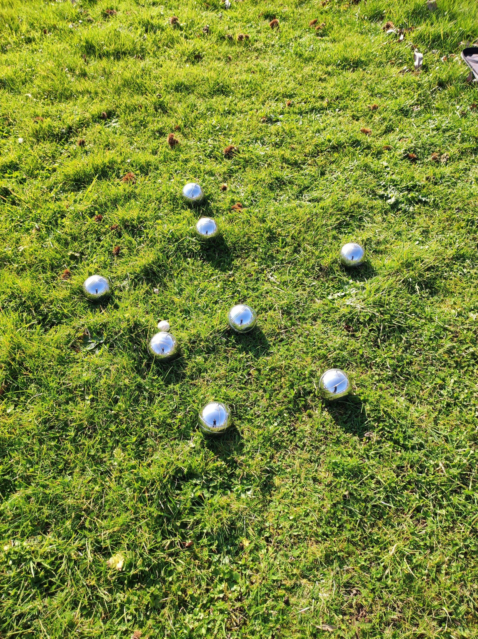 8 boules balls spread out on grass