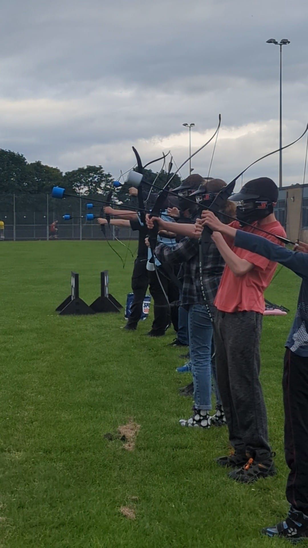 Archery Tag adventurous activity instructor led hire. Participants lined up to practice shooting the foam tipped arrows.
