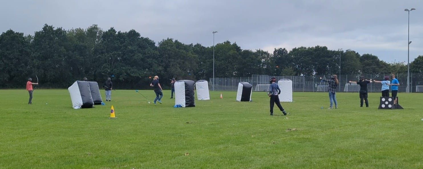 A group playing archery tag. Hiding behind inflatable bunkers and firing their safety arrows.