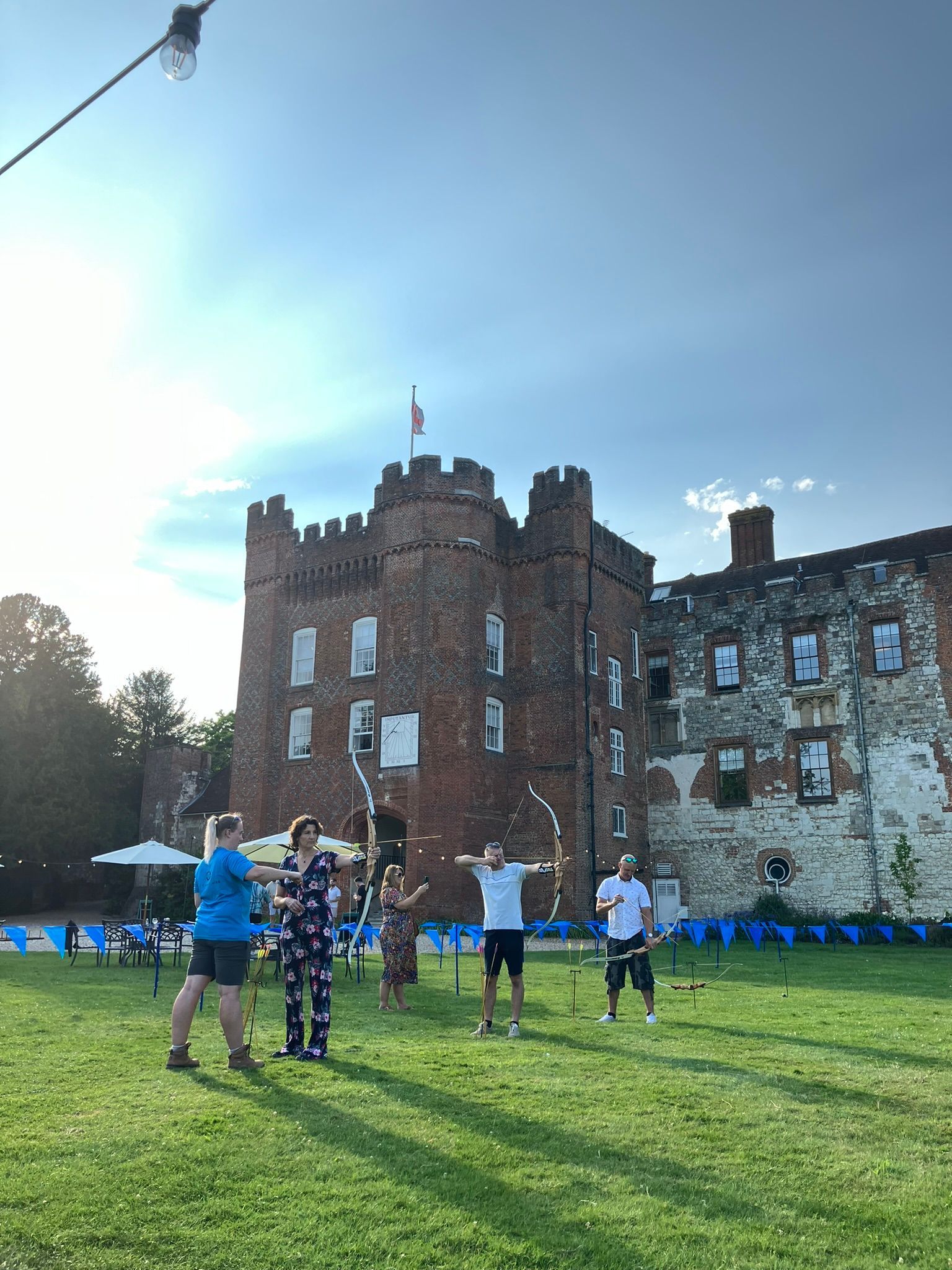 A female instructor in a blue top teaching archery at Farnham Castle