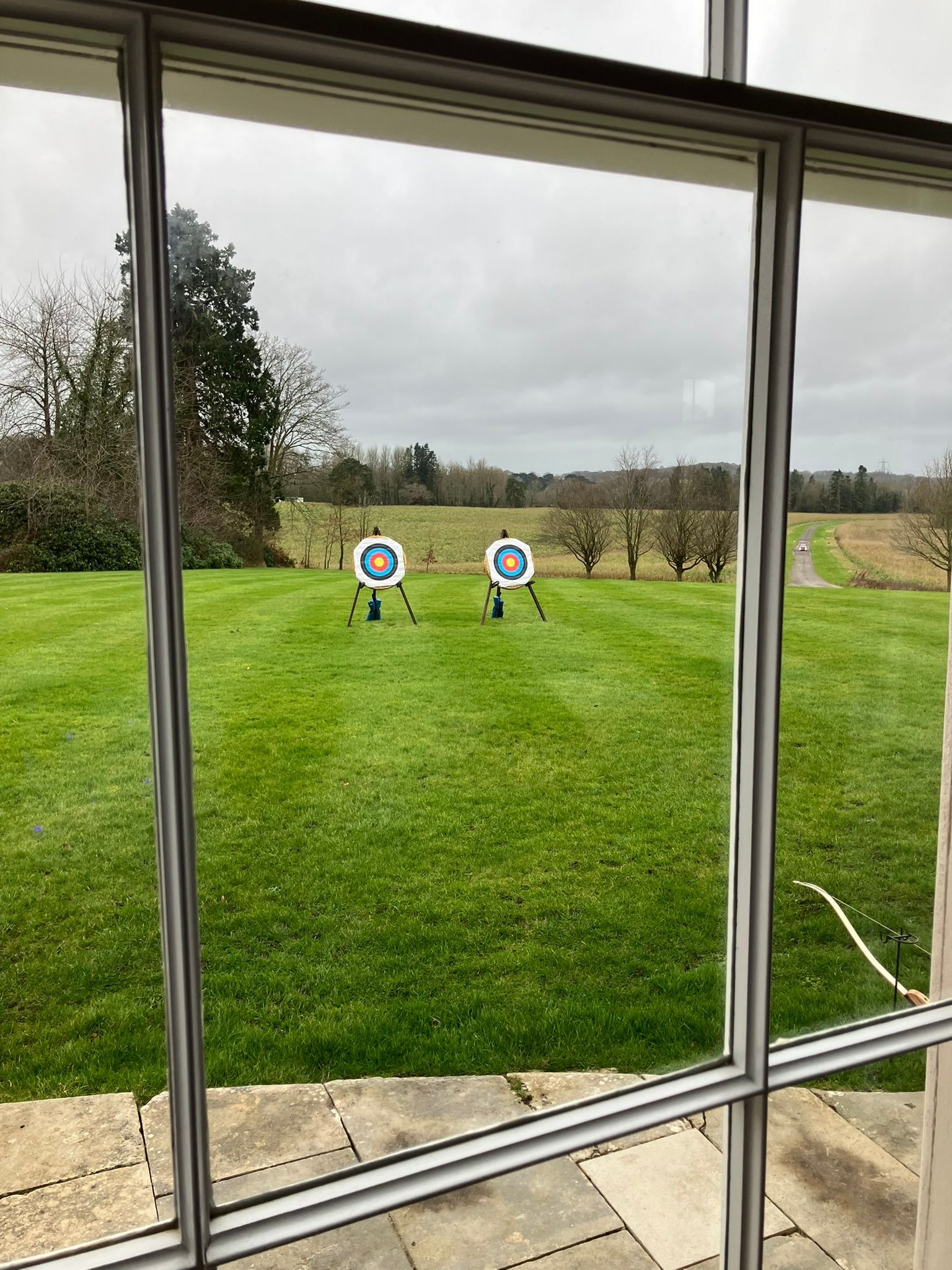 view out of a hotel window looking at 2 archery targets on stands on grass 