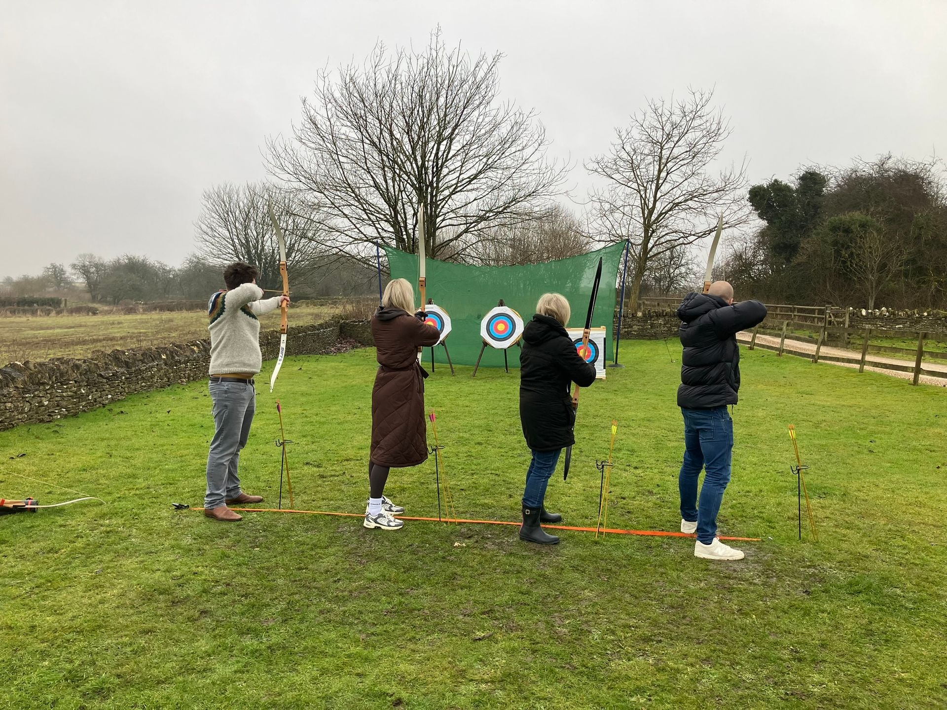 Three archery targets set up in a field in Hampshire with 4 people aiming