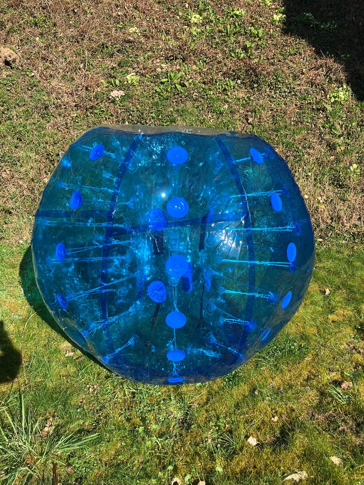 A giant blue blow up bubble football on grass.
