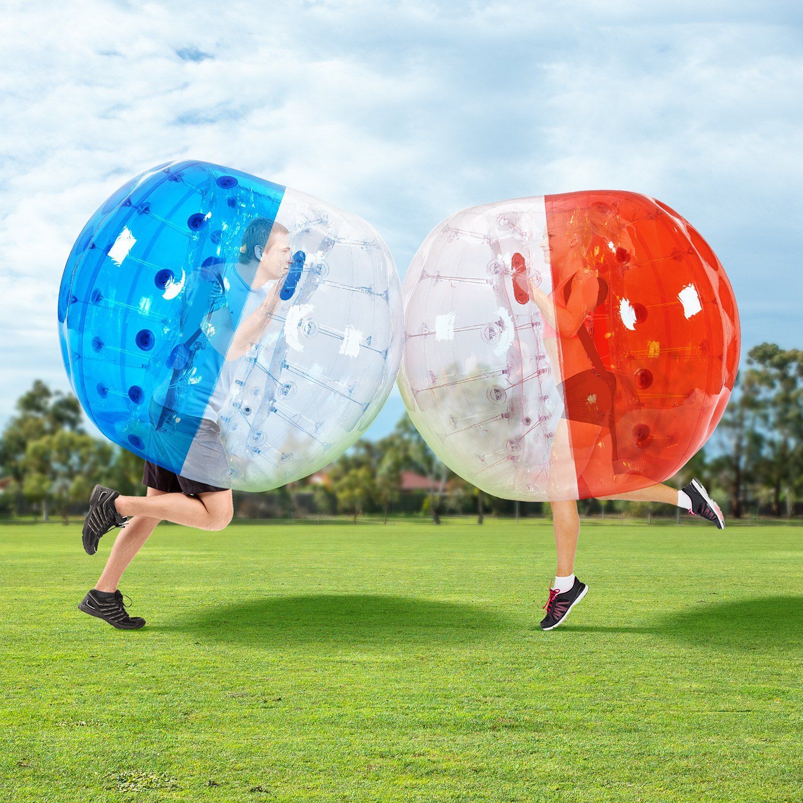 Two giant blow up bubble football balls. them on a green field, facing each other.