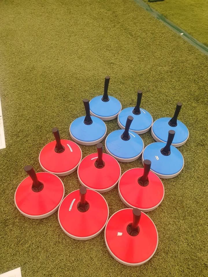 6 blue and 6 red Bavarian curling stones on green astro turf