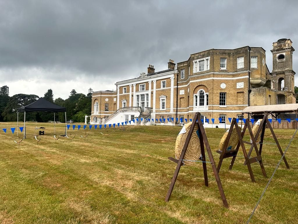 A white field on the grounds of a hotel. A corporate archery event with 3 targets.