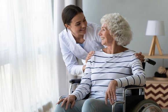 Caregiver assisting elderly resident in wheelchair at Adrian Bay Rehab & Nursing Center