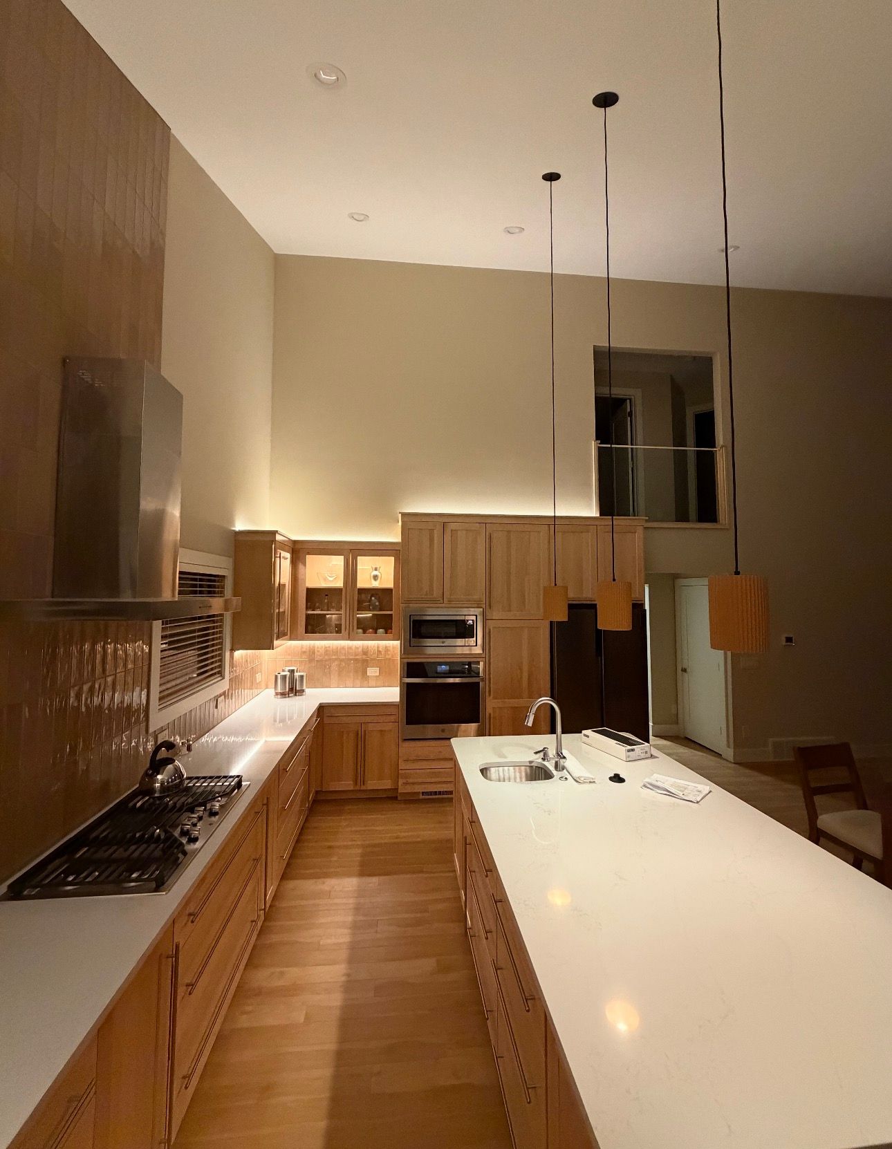 Custom kitchen lighting installation showing pendant lights and recessed LED fixtures.