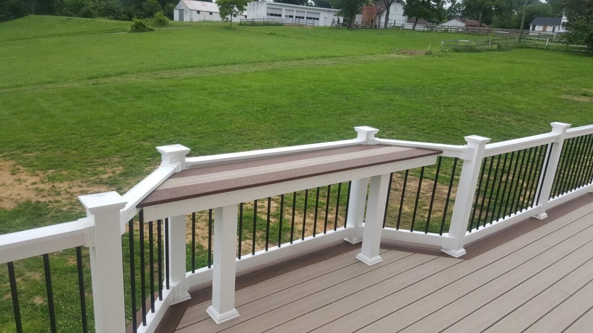 White deck railing overlooking a green lawn and distant houses on a cloudy day