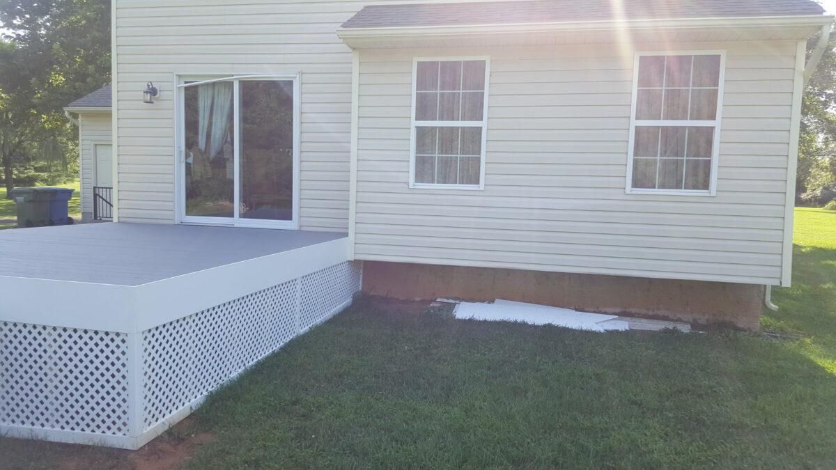 House exterior with a white lattice ramp and beige siding beside a grassy yard
