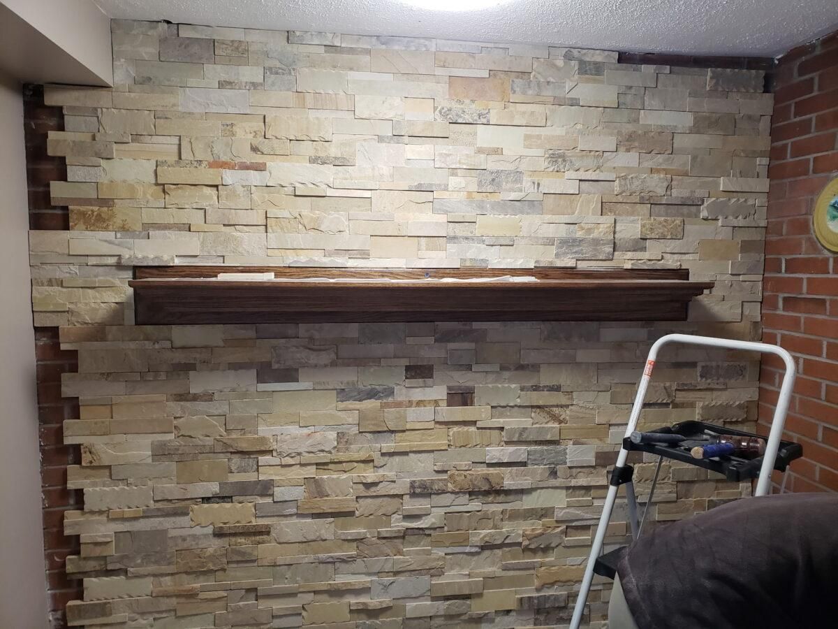 Stone accent wall with a dark wooden mantel shelf and a step ladder at right.