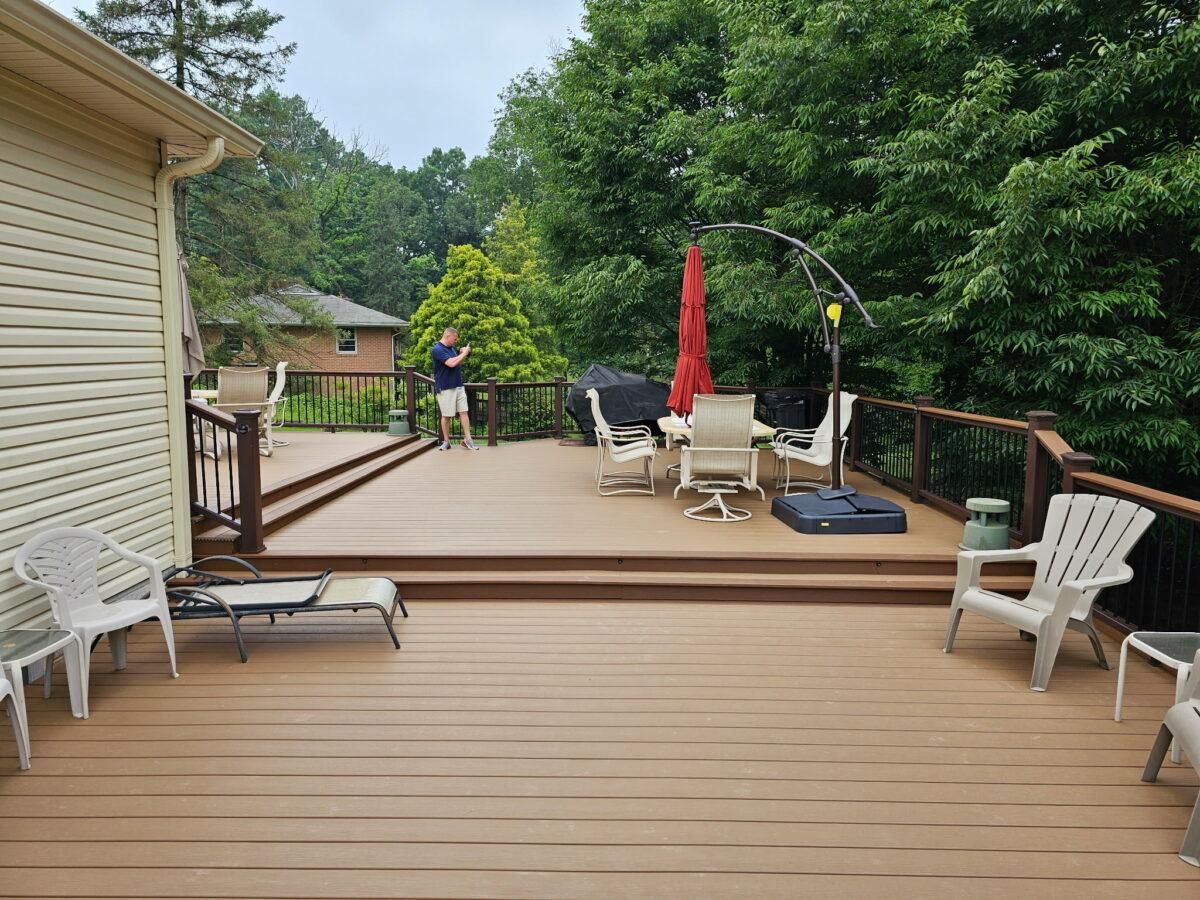 Backyard deck with chairs, red umbrella, and a person standing near the railing