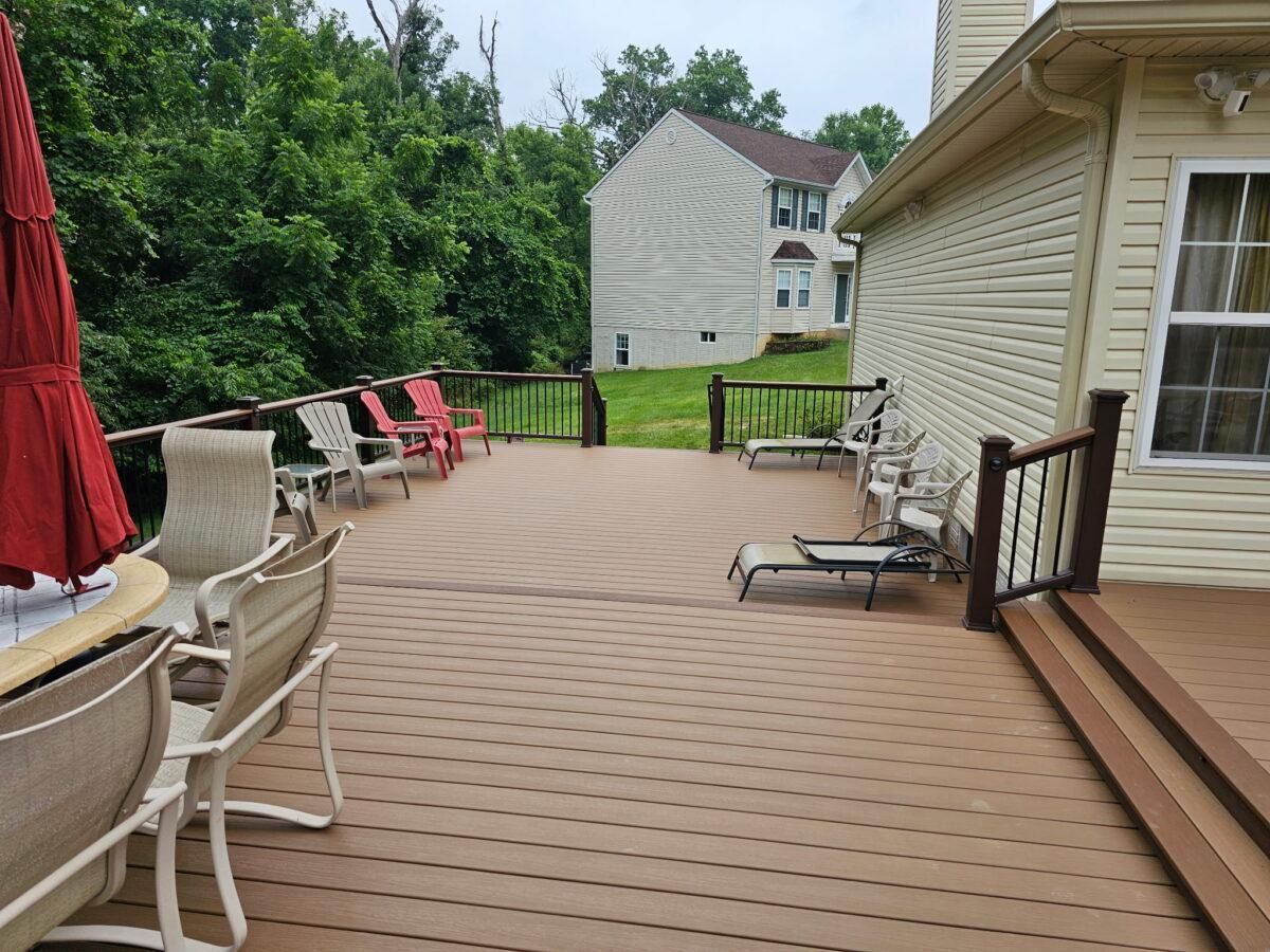 Back deck with outdoor furniture, red chairs, and a view of a grassy yard and neighboring house