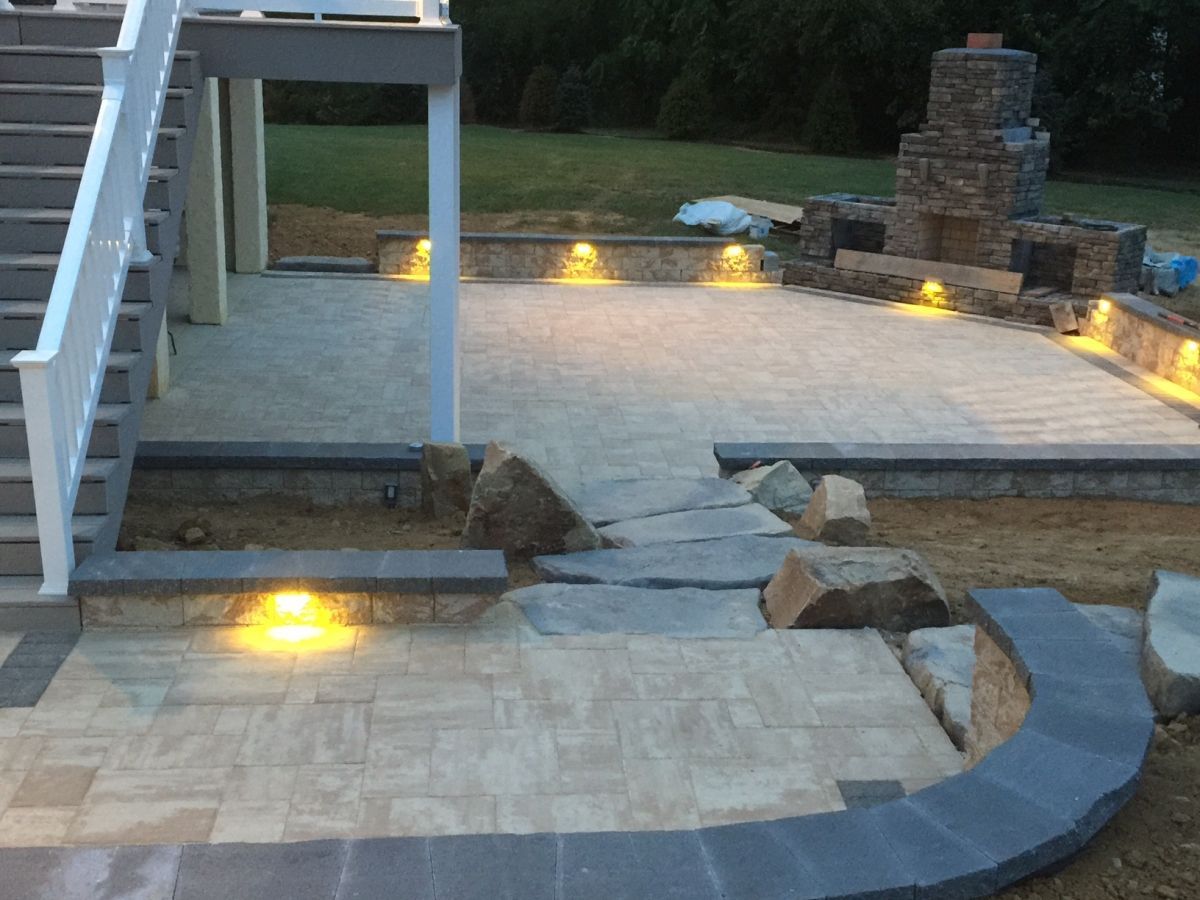 Stone patio with built-in steps, curved bench, and small ground lights at dusk